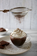 Cup of coffee with cream on color wooden background
