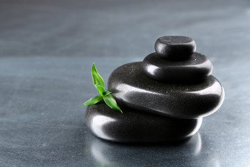 Stack of spa stones with green leaves on gray background