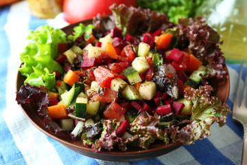 Wooden bowl of fresh vegetable salad on table, closeup