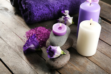 Obraz na płótnie Canvas Spa still life with towels, pebbles, purple flowers and candlelight on wooden table, closeup