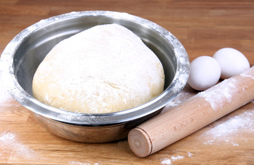 pastry baking: dough in bowl, rolling pin, flour and eggs
