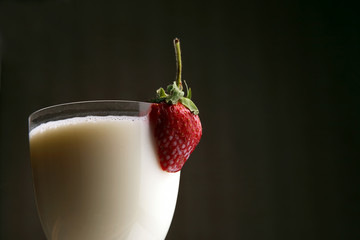 cut strawberries in a glass with milk