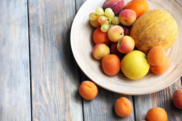 Heap of fresh fruits on tray on wooden table close up