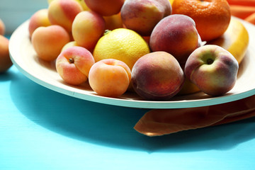 Heap of fresh fruits on tray on wooden table close up