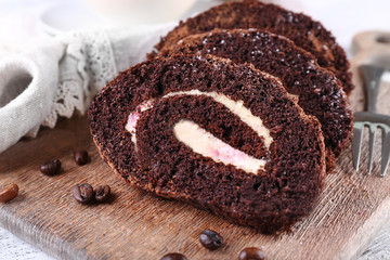 Delicious chocolate roll on wooden cutting board, closeup