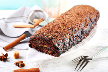 Delicious chocolate roll with spices on wooden table, closeup