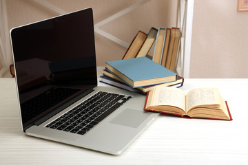 Laptop with books on table in room