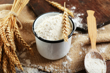 Whole flour with wheat on wooden table, closeup
