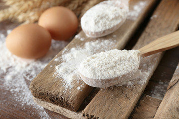 Fototapeta na wymiar Whole flour with wheat and eggs on wooden table, closeup