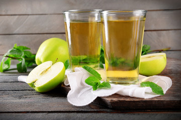 Glasses of apple juice on wooden background