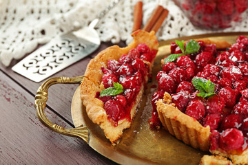 Tart with raspberries on tray, on wooden background