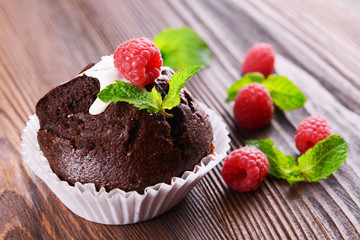 Delicious chocolate cupcake with berries on wooden table close up