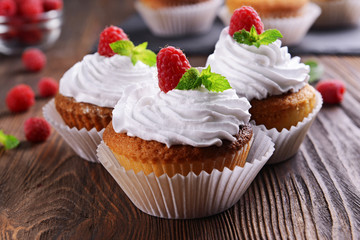 Delicious cupcakes with berries and fresh mint on wooden table close up