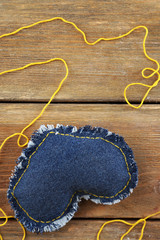 Denim heart and thread on wooden background