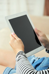Female hand holding PC tablet on home interior background
