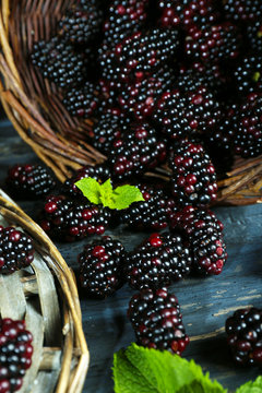 Heap of sweet blackberries with mint in basket on table close up