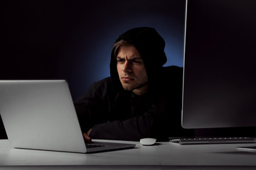 Hacker with computer and laptop on dark background