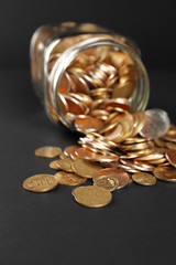 Glass jar with coins on dark background