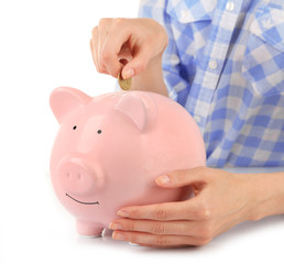 Female hands putting coin into pink piggy bank isolated on white