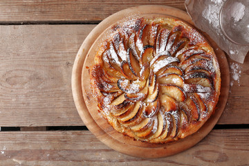 Homemade apple pie on cutting board on wooden background
