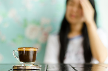 The woman,when not drink the cup of coffee, have a headache