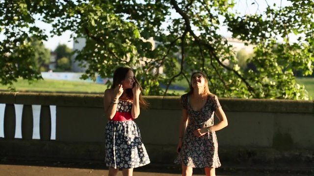 Cute teen girls girlfriends jump in the Park under a tree.

