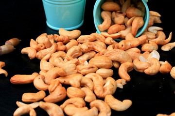 heap cashew nuts and salt on black background