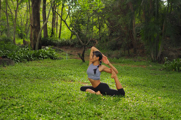 Young woman doing yoga exercises in the garden park