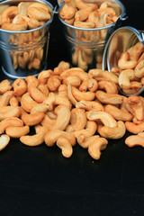 heap cashew nuts and salt on black background