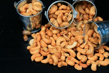 heap cashew nuts and salt on black background