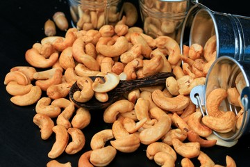 Naklejka premium heap cashew nuts and salt on black background