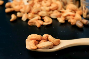 heap cashew nuts and salt on black background