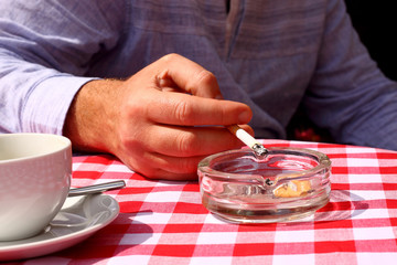Man smoking outdoor café.
Man smoking a cigarette at a café outside.