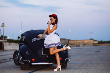 Beautiful pin-up girl posing with hot road car