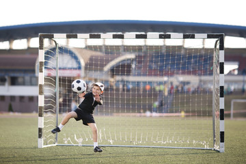boy plays football on stadium