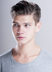 Handsome young man with fashion hairstyle over gray background.