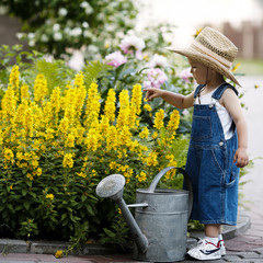 little boy with watering can in summer park
