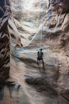 Woman rapelling down in slot canyon, canyoneering, Moab, Utah
