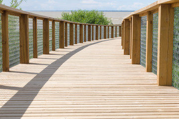 Wooden plank path with safety fence leading to the sea shore