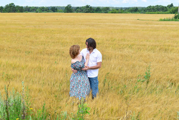 Loving middle-aged couple standing in field in summer