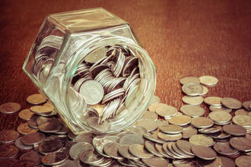 Coins spilling out of a glass bottle with filter effect retro vi