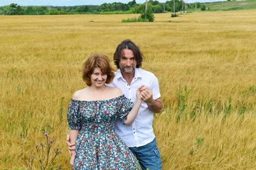 Loving middle-aged couple standing in field in summer