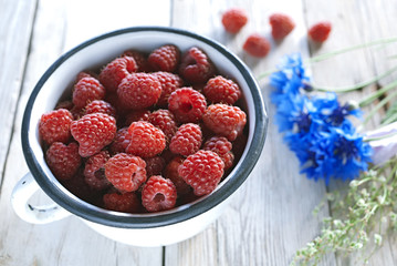 raspberries bowl on wooden table with cornflowers