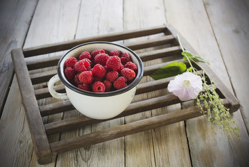 fresh raspberries in a bowl with flower on wooden table