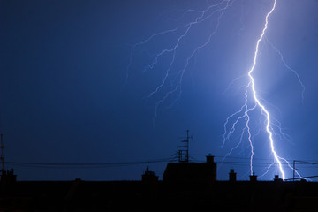 Lightning hitting city building rooftop in thunderstorm
