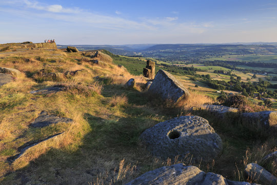 Friends on Curbar Edge with boulders and a millstone in summer, Peak District National Park, Derbyshire