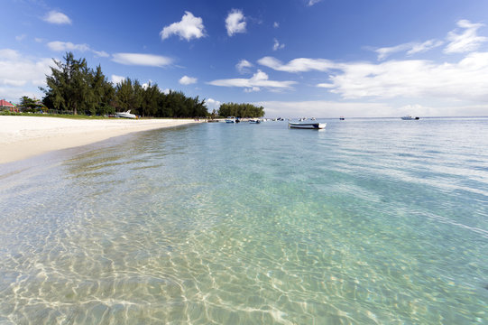View along Flic en Flac Beach showing the clear shallows of the Indian Ocean, blue sky and white sand, on the west coast of Mauritius