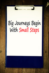 Text big journeys begin with small steps on note paper.