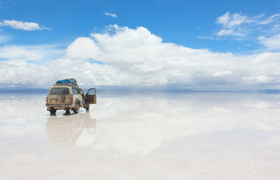 Car on the reflected surface of Salar de Uyuni lake in Bolivia