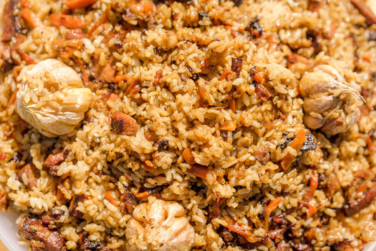 plov, national uzbek spicy meal with meat, rice, onion and garlic